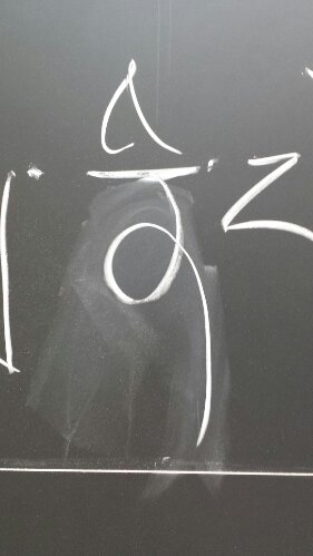 Tibetan letter NI curling to the left, visible erase marks where it was corrected